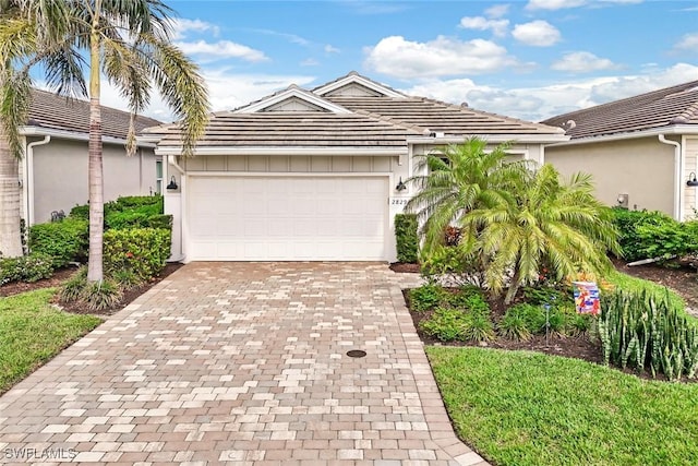 view of front facade with stucco siding, decorative driveway, an attached garage, and a tile roof