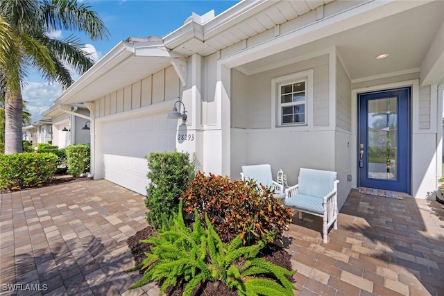 view of exterior entry featuring an attached garage and driveway