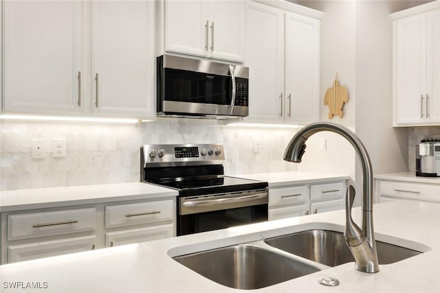 kitchen with light countertops, appliances with stainless steel finishes, decorative backsplash, and a sink