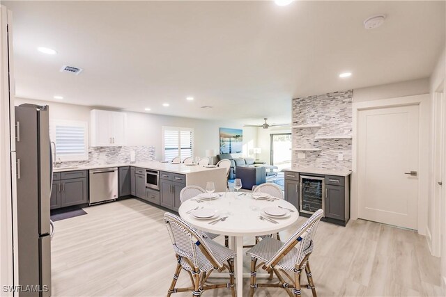 668 104th Ave N, Naples, FL 34108 - dining area with wine cooler, a ceiling fan, light wood-type flooring, and a wealth of natural light