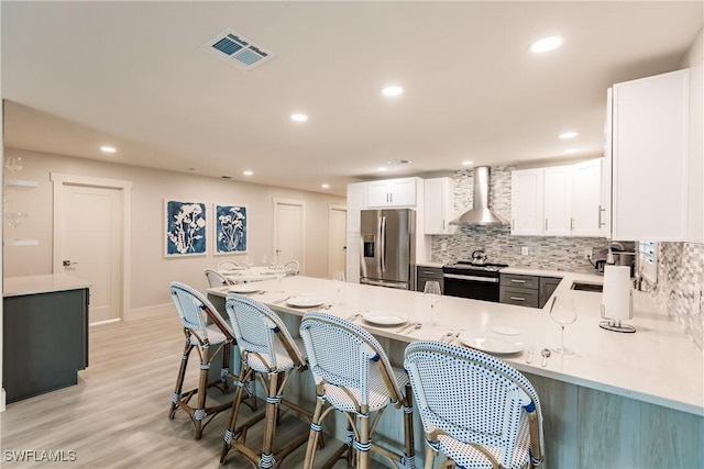 668 104th Ave N, Naples, FL 34108 - kitchen with decorative backsplash, wall chimney range hood, stainless steel refrigerator with ice dispenser, white cabinetry, and range with electric cooktop