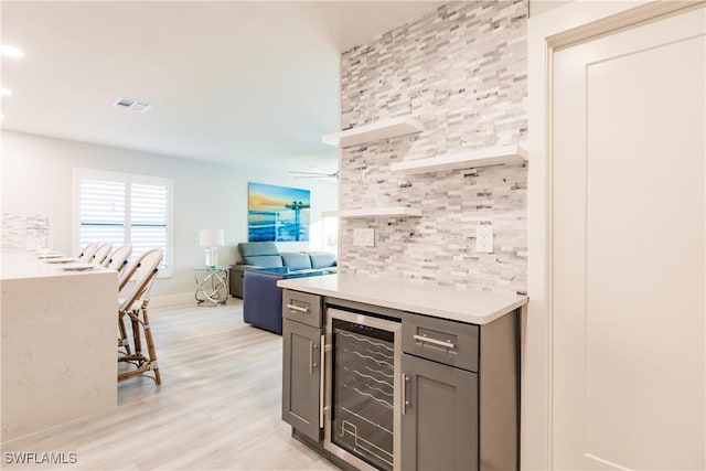 668 104th Ave N, Naples, FL 34108 - bar with beverage cooler, light wood-type flooring, backsplash, visible vents, and a bar