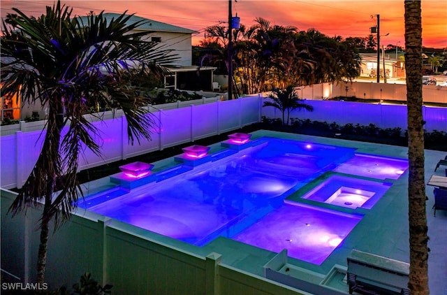 668 104th Ave N, Naples, FL 34108 - pool at dusk featuring a fenced backyard and a pool with connected hot tub
