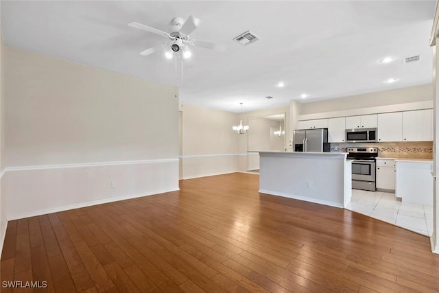 20657 Country Barn Dr, Estero, FL 33928 - unfurnished living room with visible vents, light wood finished floors, recessed lighting, and ceiling fan with notable chandelier