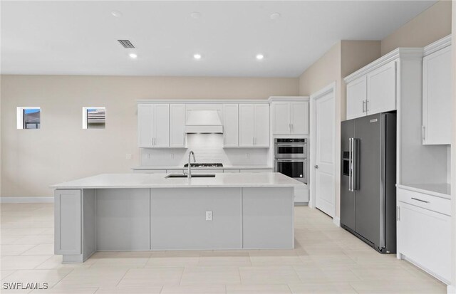 7060 Del Webb Oak Creek Blvd, North Fort Myers, FL 33917 - kitchen featuring appliances with stainless steel finishes, light countertops, white cabinetry, an island with sink, and tasteful backsplash