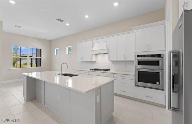 7060 Del Webb Oak Creek Blvd, North Fort Myers, FL 33917 - kitchen with a sink, custom range hood, appliances with stainless steel finishes, a center island with sink, and light countertops