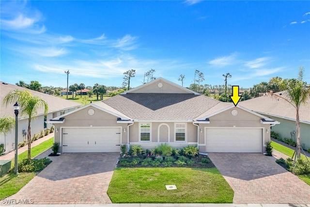 ranch-style home with stucco siding, an attached garage, and decorative driveway