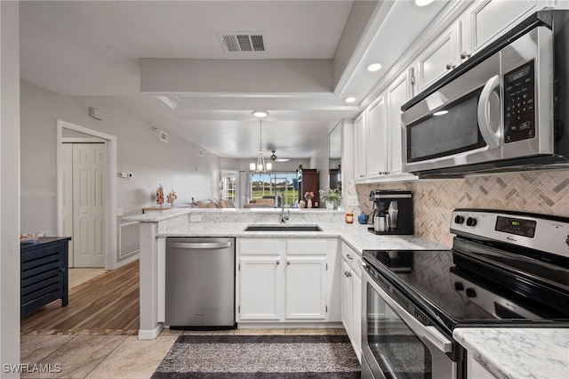kitchen with visible vents, a raised ceiling, a sink, a peninsula, and stainless steel appliances