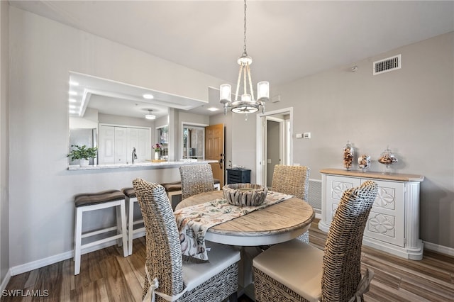 dining room with a chandelier, visible vents, baseboards, and wood finished floors