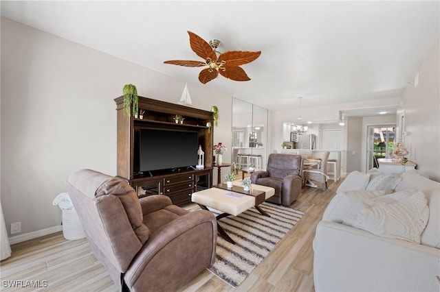 living area with light wood-style flooring and ceiling fan with notable chandelier