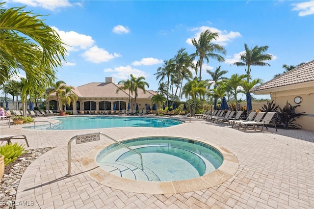 community pool with a patio area and a hot tub