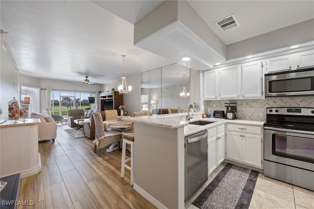 kitchen with visible vents, a sink, open floor plan, appliances with stainless steel finishes, and white cabinetry