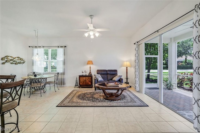 living area with light tile patterned flooring, a ceiling fan, and baseboards