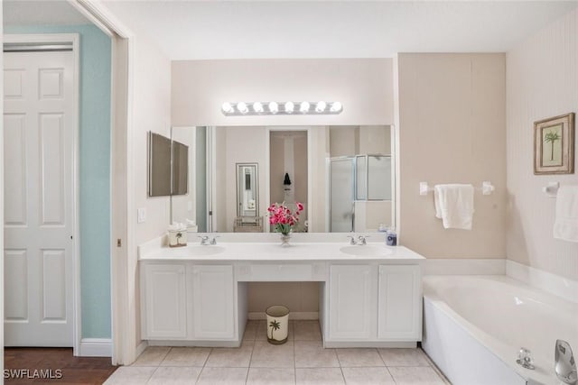 bathroom with double vanity, a garden tub, tile patterned flooring, a stall shower, and a sink