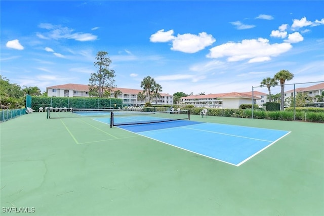 view of tennis court featuring fence and a residential view