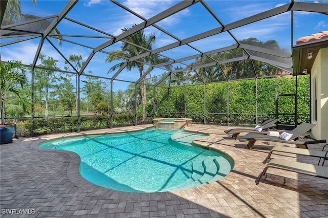 view of swimming pool featuring a patio area, a pool with connected hot tub, and glass enclosure