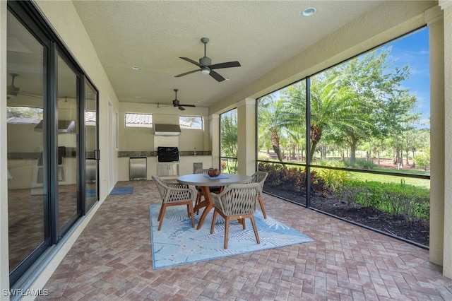sunroom featuring outdoor dining area and ceiling fan