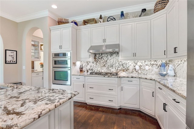 kitchen featuring white cabinetry, arched walkways, under cabinet range hood, and appliances with stainless steel finishes