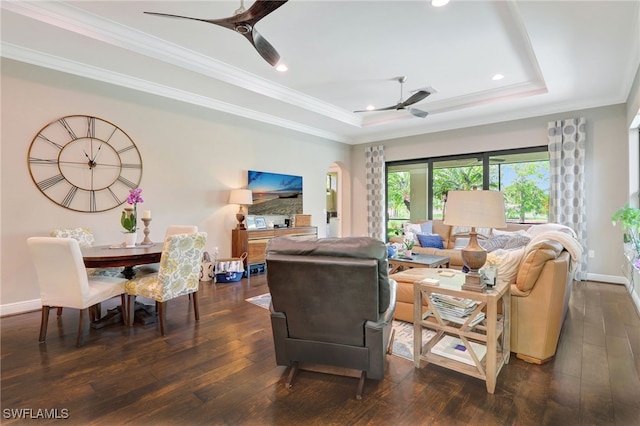 living area with baseboards, a ceiling fan, a tray ceiling, and dark wood-style floors