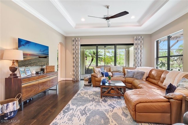 living area featuring hardwood / wood-style floors, a raised ceiling, a ceiling fan, arched walkways, and crown molding