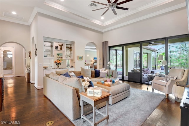 living room with arched walkways, visible vents, a ceiling fan, and ornamental molding