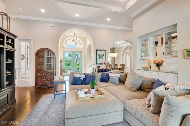 living room featuring dark wood-style flooring, crown molding, arched walkways, a notable chandelier, and recessed lighting