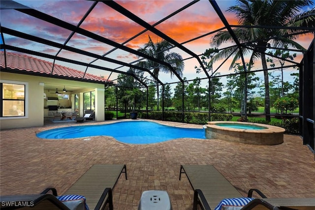 14501 Marsala Way, Naples, FL 34109 - pool at dusk with a patio, a pool with connected hot tub, a ceiling fan, and glass enclosure