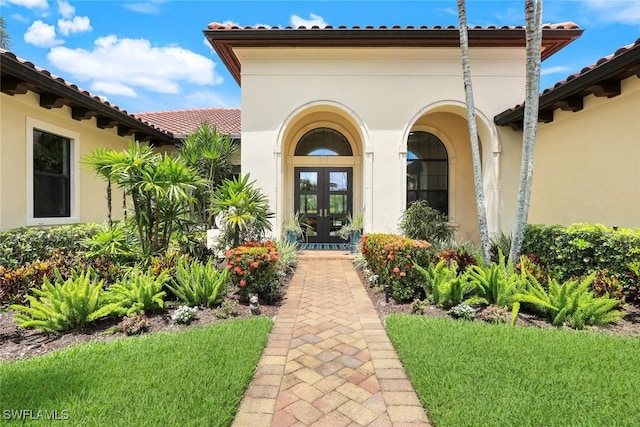 14501 Marsala Way, Naples, FL 34109 - entrance to property with french doors, stucco siding, a tile roof, and a lawn