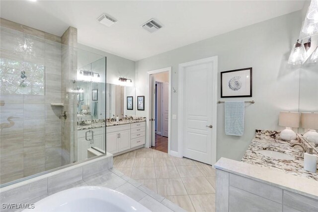 14501 Marsala Way, Naples, FL 34109 - full bathroom with a stall shower, two vanities, a bathtub, and tile patterned flooring