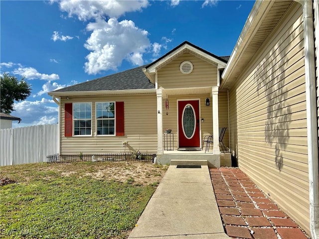 property entrance featuring fence and roof with shingles