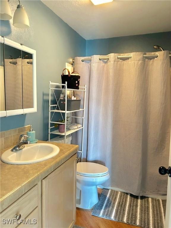 bathroom featuring vanity, a shower with curtain, toilet, lofted ceiling, and wood finished floors