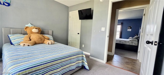 bedroom featuring a closet, tile patterned floors, carpet, and baseboards