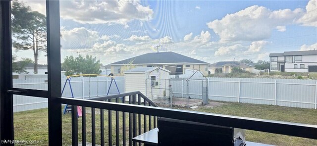 deck featuring a residential view, a fenced backyard, an outdoor structure, and a yard