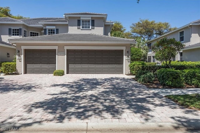 7099 Pond Cypress Ct Unit 102, Naples, FL 34109 - view of front of property with decorative driveway, a tiled roof, stucco siding, and a garage