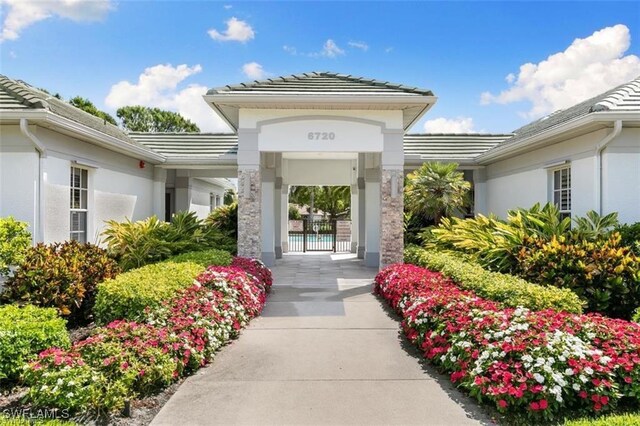 7099 Pond Cypress Ct Unit 102, Naples, FL 34109 - doorway to property featuring a tiled roof and stucco siding
