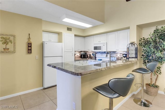 1150 Wildwood Lakes Blvd Unit 306, Naples, FL 34104 - kitchen featuring white cabinets, white appliances, a peninsula, and dark stone counters