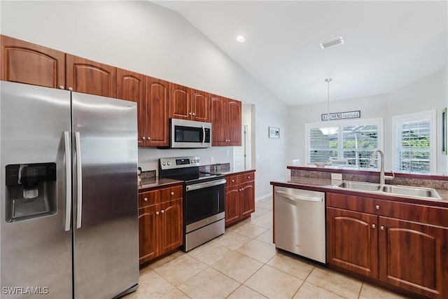 kitchen with a sink, light tile patterned floors, high vaulted ceiling, hanging light fixtures, and appliances with stainless steel finishes