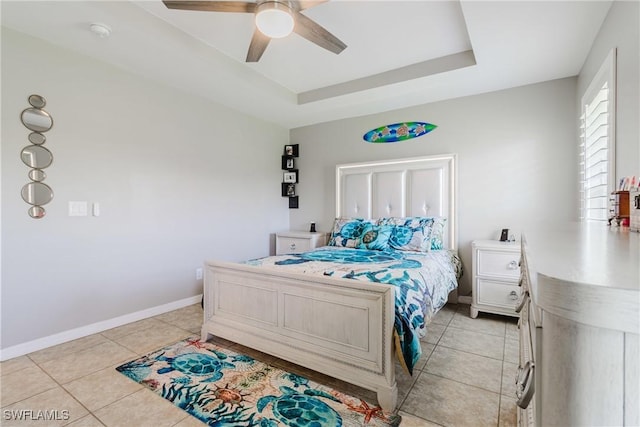 bedroom featuring light tile patterned floors, a raised ceiling, ceiling fan, and baseboards