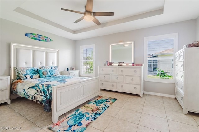 bedroom with light tile patterned floors, ceiling fan, baseboards, and a tray ceiling