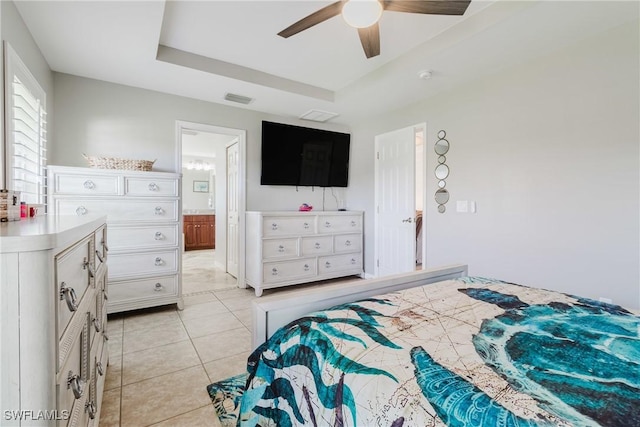 bedroom with connected bathroom, light tile patterned floors, ceiling fan, visible vents, and a raised ceiling