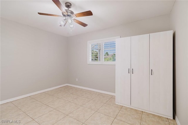 unfurnished bedroom with light tile patterned floors, a ceiling fan, and baseboards