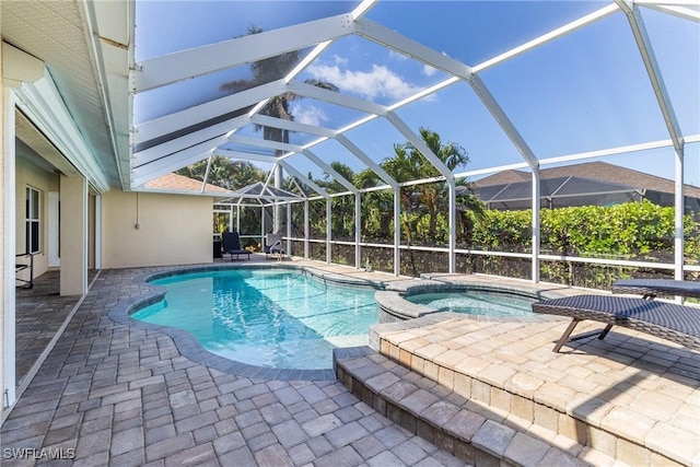 view of swimming pool with glass enclosure, a pool with connected hot tub, and a patio area