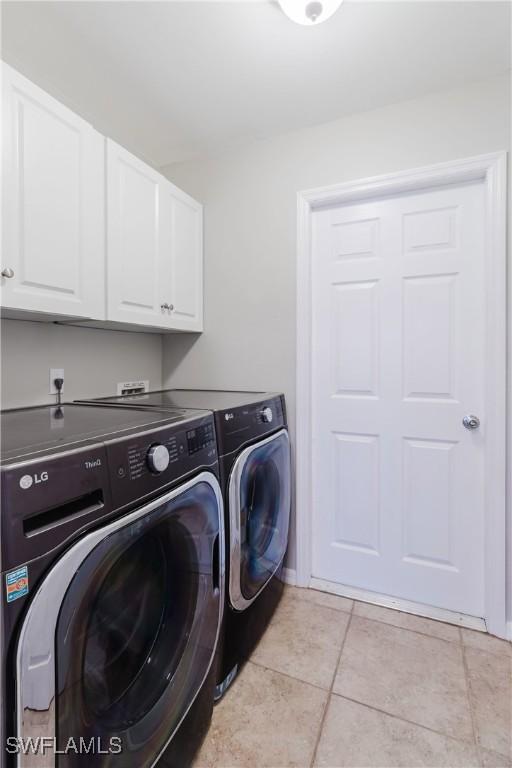 laundry area with light tile patterned flooring, cabinet space, and washing machine and dryer