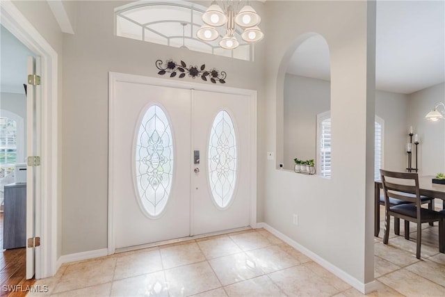 foyer featuring an inviting chandelier, arched walkways, and baseboards