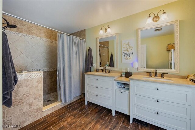 3322 SW 29th Ave, Cape Coral, FL 33914 - full bathroom with a sink, a tile shower, double vanity, and wood finished floors