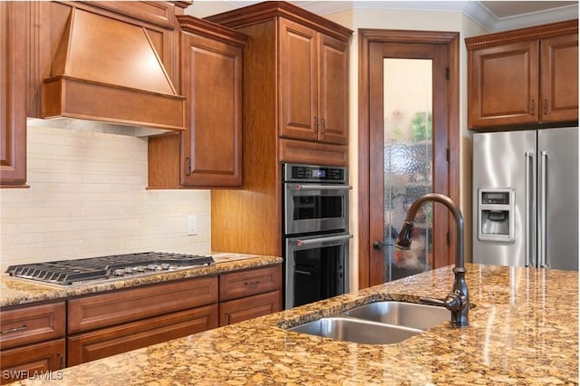 kitchen featuring a sink, decorative backsplash, stainless steel appliances, premium range hood, and light stone countertops