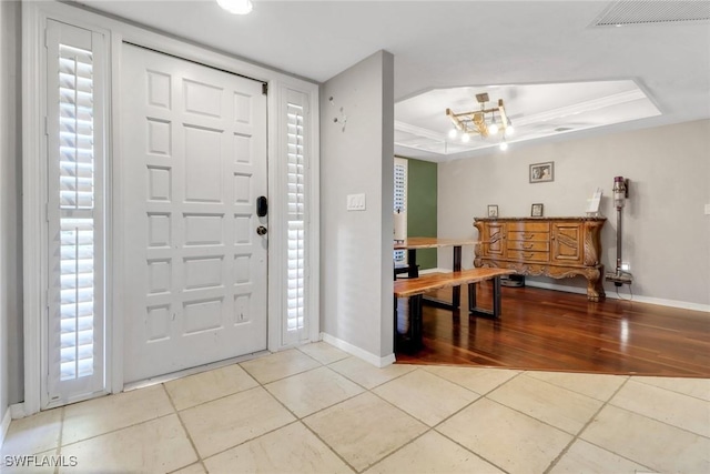 foyer with a raised ceiling, baseboards, visible vents, and light tile patterned floors