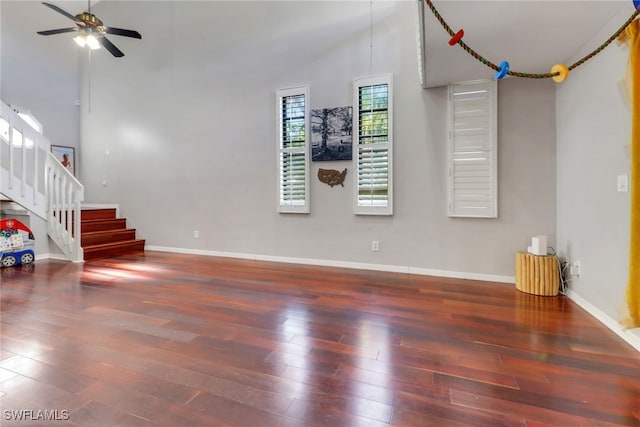 unfurnished living room with hardwood / wood-style flooring, ceiling fan, baseboards, and stairs