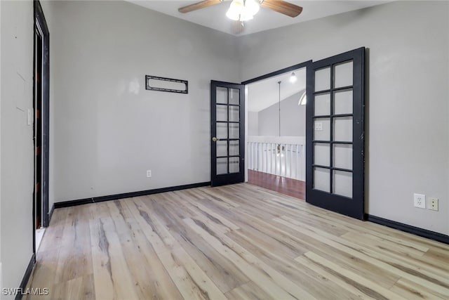 spare room featuring vaulted ceiling, wood finished floors, a ceiling fan, and french doors