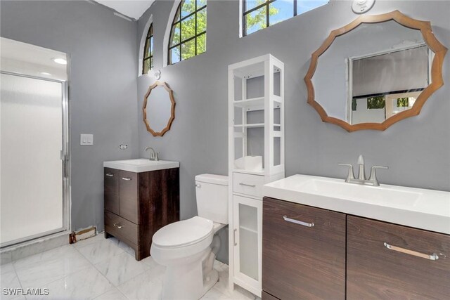 bathroom featuring a sink, two vanities, a shower stall, and toilet